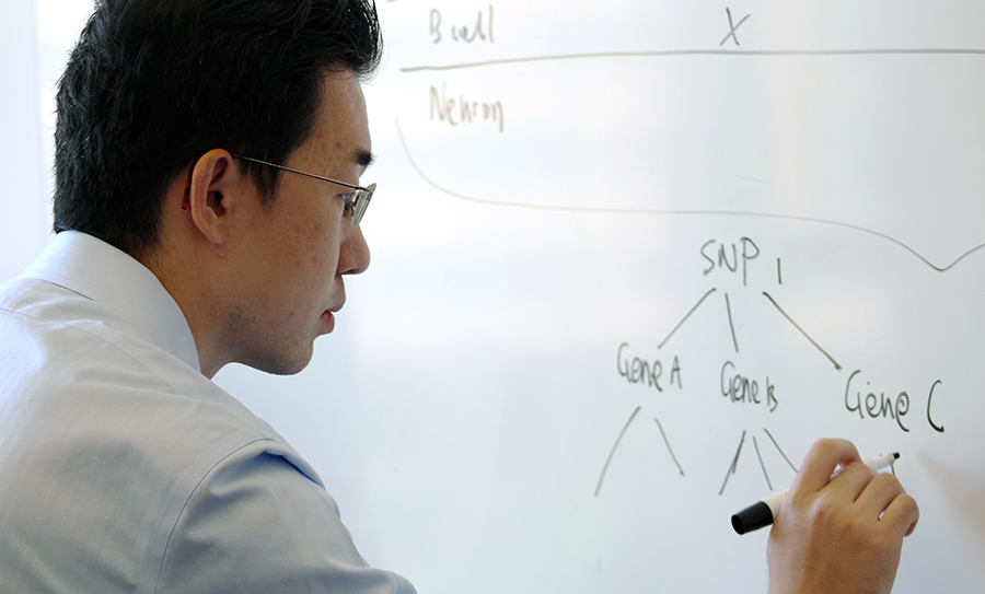  A man writes on a dry erase board with black marker.
