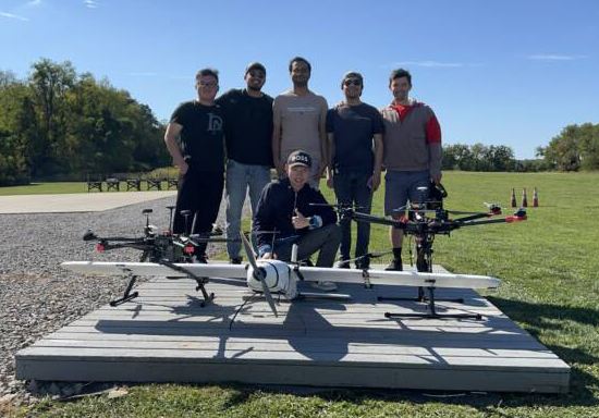  Six men pose in a park environment with an assortment of drones.