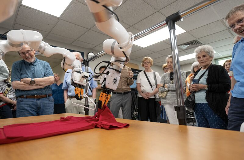 people watching a robot arm demonstration
